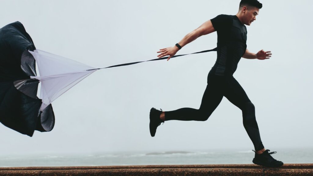 Athlete sprinting with resistance parachute for strength training—symbolizing overcoming obstacles during ERP implementation or change management challenges.