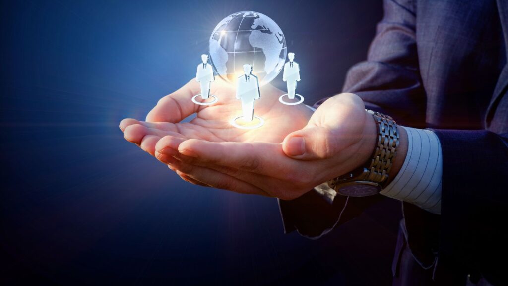 Businessperson holding holographic icons of global team members and a digital globe, symbolizing international collaboration and multi-entity management.