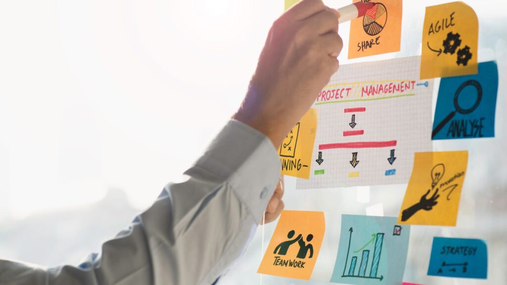 Hand arranging sticky notes and charts for project management planning, symbolizing steps in an ERP Migration Roadmap to Microsoft Dynamics 365 Business Central.