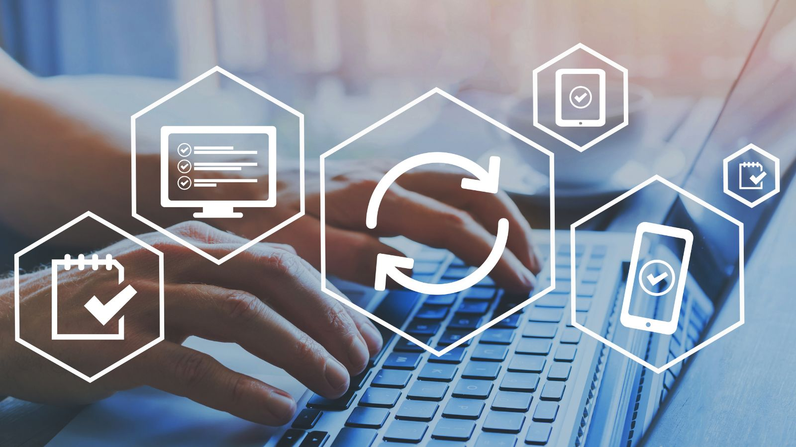 Hands typing on a laptop with overlay icons representing synchronization, task completion, and mobile access, illustrating digital workflow automation and ERP improvements in the Business Central Wave 2 2025 Update.